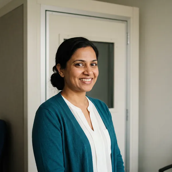 Priya Nair, smiling, standing in front of the sound booth door.