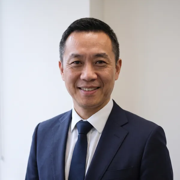Kenneth Cheung, smiling, in a navy suit