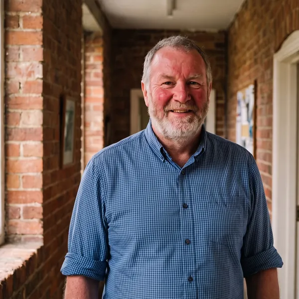 Dr Tom McKenna, grey-bearded and smiling, in a blue checked shirt in the clinic’s brick hallway.