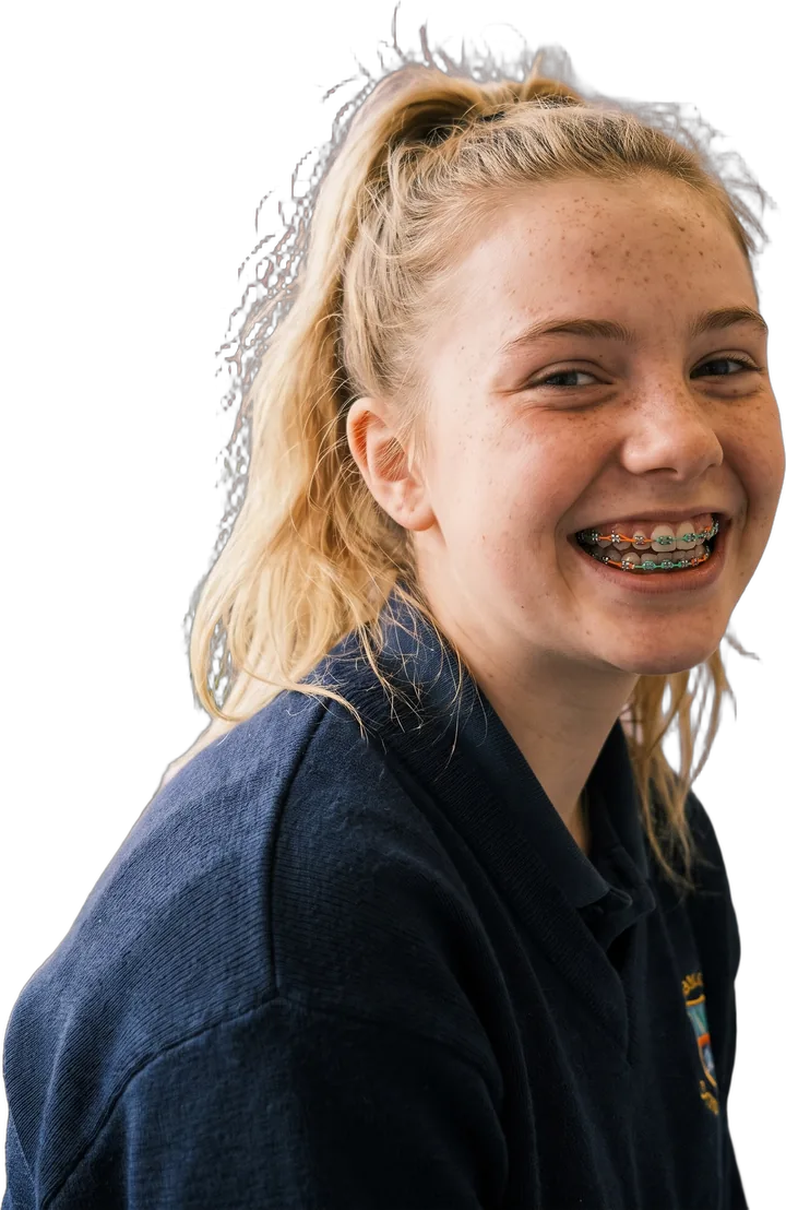 Ruby, a teenage patient, grinning with tangerine and mint bands on her braces.