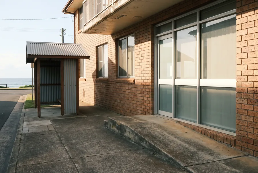 A low-rise brick office at 45 Mann Street with a concrete ramp up to the glass front door